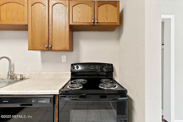 kitchen featuring black appliances, light countertops, and a sink