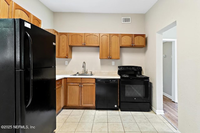 kitchen featuring black appliances, a sink, light countertops, light tile patterned floors, and baseboards