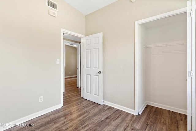 unfurnished bedroom with wood finished floors, a closet, and baseboards