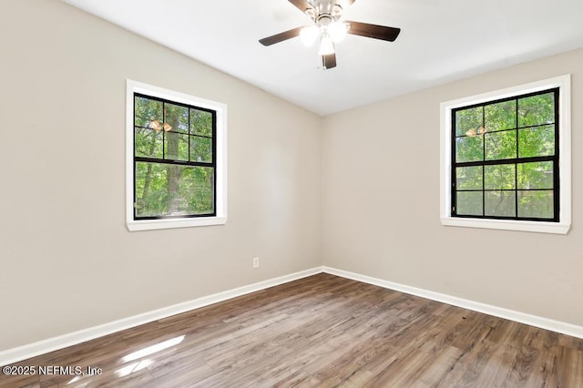 empty room with wood finished floors, baseboards, and a ceiling fan