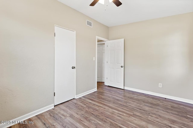 unfurnished bedroom featuring wood finished floors, baseboards, and a ceiling fan