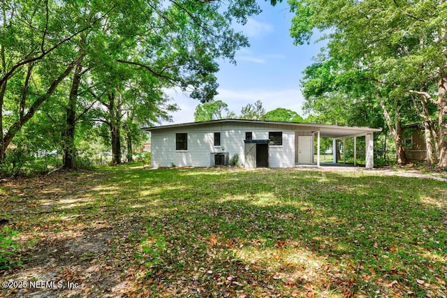 rear view of house with an attached carport, a lawn, and cooling unit
