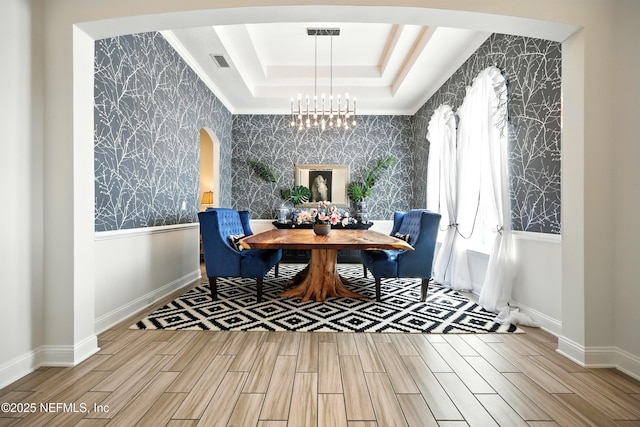 2919 Brettungar Dr, Jacksonville, FL 32224 - dining space with wallpapered walls, arched walkways, a chandelier, wood tiled floors, and a raised ceiling