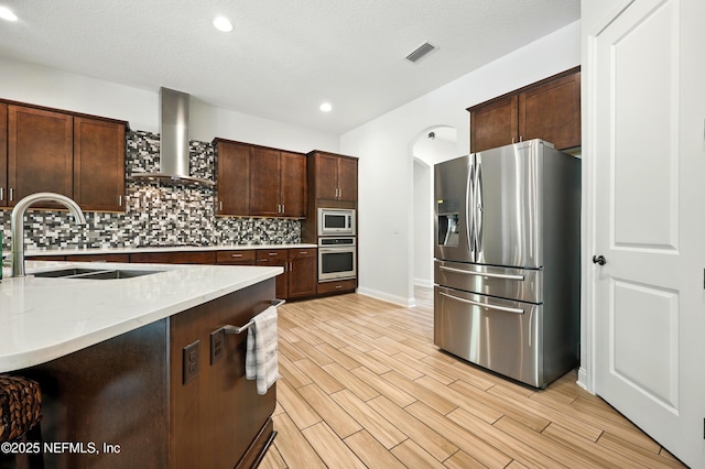 2919 Brettungar Dr, Jacksonville, FL 32224 - kitchen with appliances with stainless steel finishes, wall chimney range hood, tasteful backsplash, recessed lighting, and dark brown cabinets