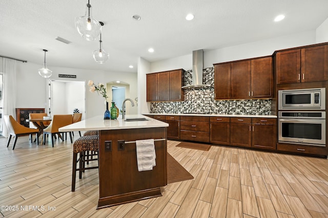 2919 Brettungar Dr, Jacksonville, FL 32224 - kitchen featuring appliances with stainless steel finishes, wall chimney range hood, light countertops, light wood finished floors, and recessed lighting