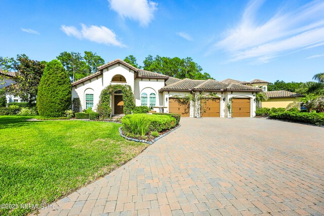 2919 Brettungar Dr, Jacksonville, FL 32224 - mediterranean / spanish home with stucco siding, a garage, a front lawn, driveway, and a tile roof