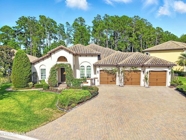 2919 Brettungar Dr, Jacksonville, FL 32224 - mediterranean / spanish-style home featuring stucco siding, an attached garage, a tiled roof, decorative driveway, and a front yard