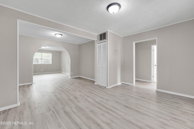 654 Woodbine St, Jacksonville, FL 32206 - unfurnished living room featuring a textured ceiling, ornamental molding, arched walkways, wood finished floors, and baseboards