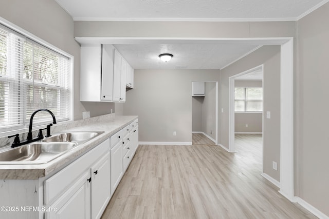 654 Woodbine St, Jacksonville, FL 32206 - kitchen featuring a sink, light wood-style flooring, white cabinets, light countertops, and crown molding