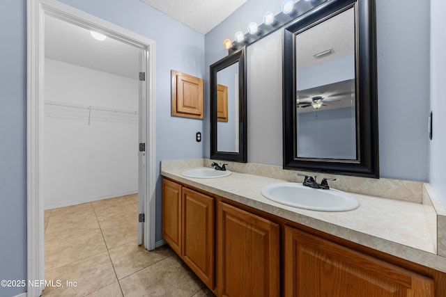 2830 Limestone Ct, Middleburg, FL 32068 - bathroom with double vanity, a spacious closet, tile patterned flooring, a textured ceiling, and a ceiling fan