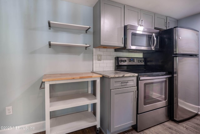 100 Fairway Park Blvd Unit 1306, Ponte Vedra Beach, FL 32082 - kitchen with stainless steel appliances, gray cabinetry, backsplash, wood finished floors, and light stone countertops