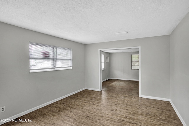 empty room with wood finished floors, a textured ceiling, and baseboards