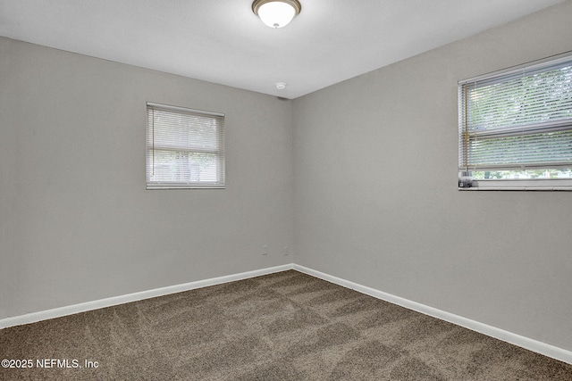 spare room with dark carpet and baseboards