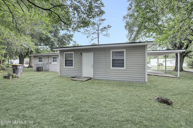 back of property featuring a yard, cooling unit, and a carport