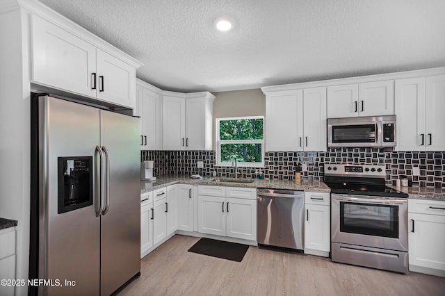 1573 Aletha Dr, Jacksonville, FL 32211 - kitchen featuring stainless steel appliances, a sink, white cabinets, light wood-type flooring, and a textured ceiling