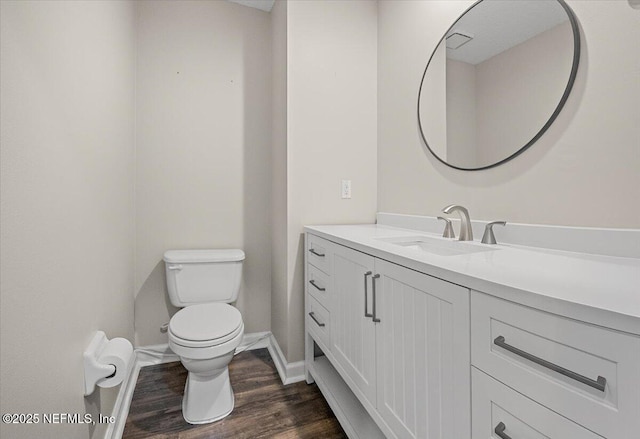 bathroom featuring toilet, wood finished floors, vanity, and baseboards