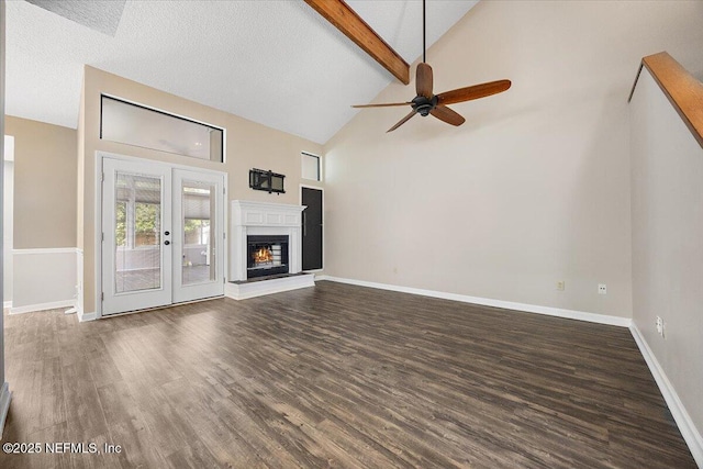 unfurnished living room with ceiling fan, dark wood finished floors, high vaulted ceiling, beam ceiling, and baseboards