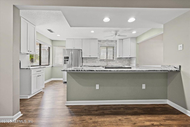 kitchen featuring stainless steel refrigerator with ice dispenser, light stone counters, white cabinetry, healthy amount of natural light, and recessed lighting
