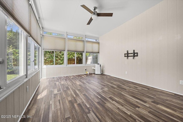 unfurnished sunroom featuring wood finished floors, ceiling fan, and wooden walls