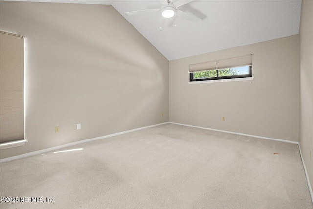 carpeted spare room with vaulted ceiling, a ceiling fan, and baseboards