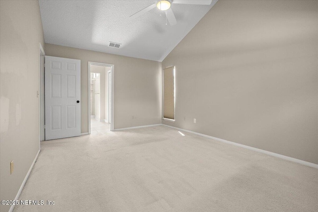 empty room featuring light colored carpet, a ceiling fan, baseboards, a textured ceiling, and lofted ceiling