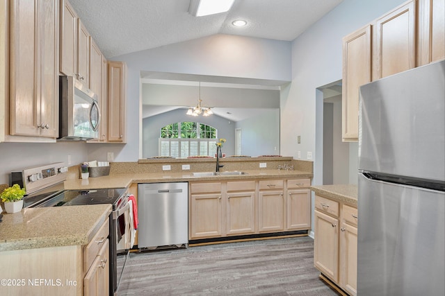 2120 Stone Creek Dr Unit E, Fleming Island, FL 32003 - kitchen featuring appliances with stainless steel finishes, a sink, lofted ceiling, light brown cabinets, and a textured ceiling