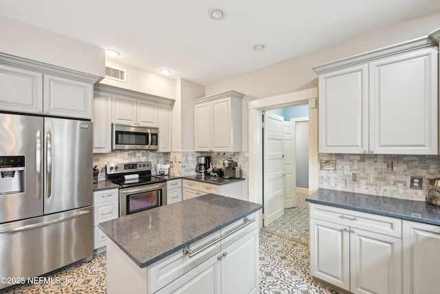 16 May St, Saint Augustine, FL 32084 - kitchen with stainless steel appliances, decorative backsplash, dark stone counters, recessed lighting, and a kitchen island