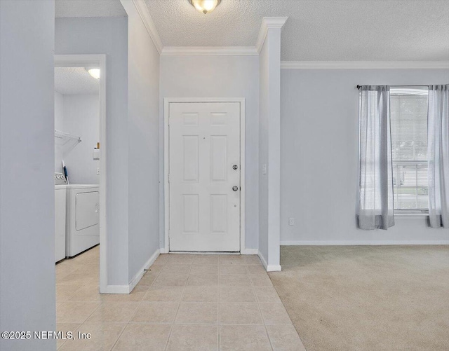 foyer entrance with washing machine and clothes dryer, a textured ceiling, crown molding, light tile patterned floors, and baseboards