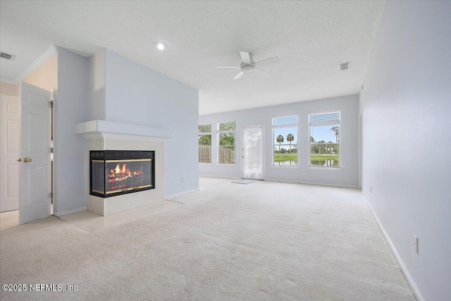 unfurnished living room with ceiling fan, carpet floors, a textured ceiling, a multi sided fireplace, and baseboards