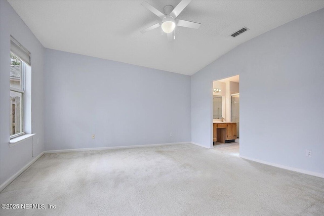 spare room with vaulted ceiling, a ceiling fan, light colored carpet, and baseboards