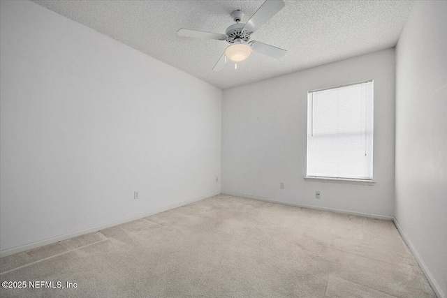spare room with carpet, a textured ceiling, ceiling fan, and baseboards