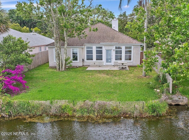 rear view of property featuring a chimney, a patio area, stucco siding, and a water view