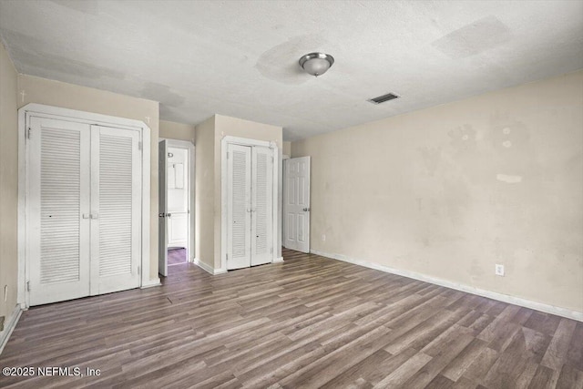 7972 Waxwing Ave, Jacksonville, FL 32219 - unfurnished bedroom with multiple closets, wood finished floors, baseboards, and a textured ceiling