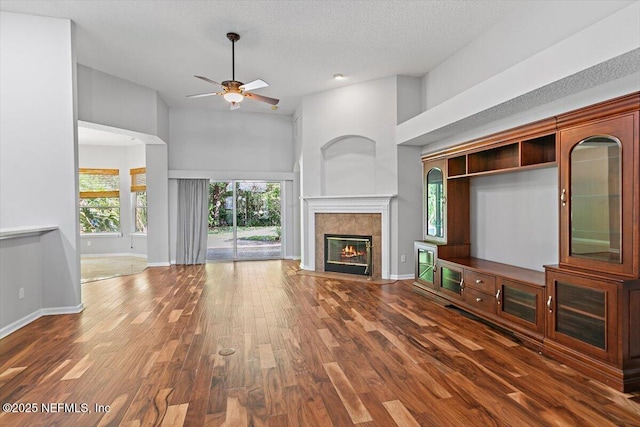 663 Reflection Cove Ct, Jacksonville, FL 32218 - unfurnished living room with a ceiling fan, a fireplace, wood finished floors, baseboards, and a towering ceiling