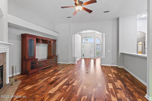 663 Reflection Cove Ct, Jacksonville, FL 32218 - unfurnished living room featuring arched walkways, dark wood-style floors, a fireplace, ceiling fan, and baseboards