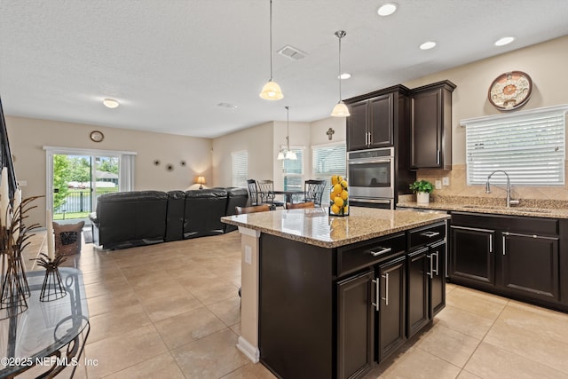 4008 Cormorant Ln, Middleburg, FL 32068 - kitchen featuring a sink, light tile patterned flooring, backsplash, open floor plan, and hanging light fixtures