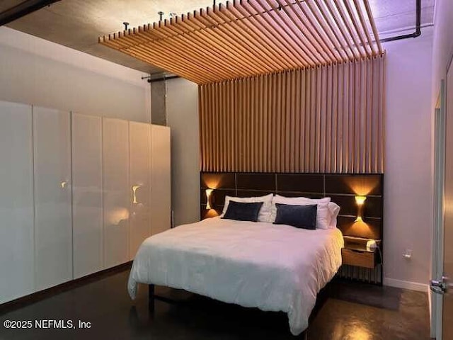 bedroom featuring baseboards and finished concrete floors