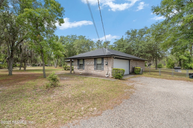 2658 Apache Ct, Middleburg, FL 32068 - view of front of house featuring fence, gravel driveway, a garage, brick siding, and roof with shingles