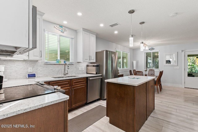 8211 Colee Cove Branch Rd Unit G, Saint Augustine, FL 32092 - kitchen with stainless steel appliances, a sink, a center island, decorative backsplash, and a textured ceiling