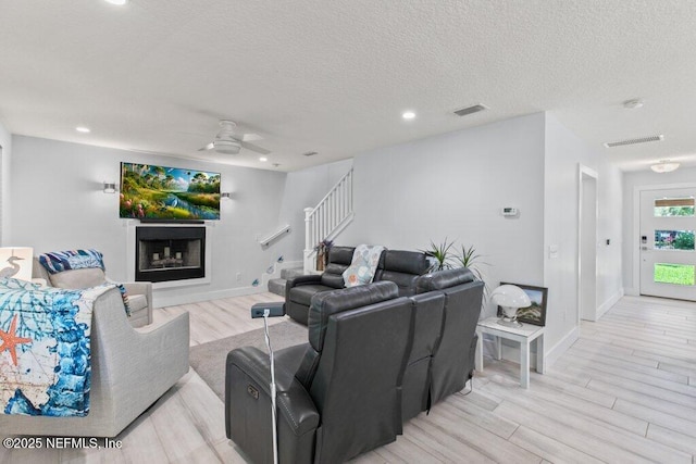 8211 Colee Cove Branch Rd Unit G, Saint Augustine, FL 32092 - living area featuring ceiling fan, light wood-style floors, a fireplace, stairs, and a textured ceiling