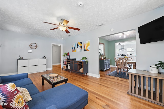 5327 Attleboro St, Jacksonville, FL 32205 - living area with light wood-type flooring, a ceiling fan, a textured ceiling, and baseboards
