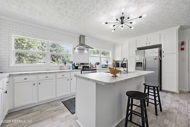 5327 Attleboro St, Jacksonville, FL 32205 - kitchen with wall chimney range hood, appliances with stainless steel finishes, a textured ceiling, a chandelier, and light wood finished floors