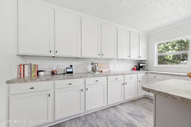 5327 Attleboro St, Jacksonville, FL 32205 - kitchen featuring a textured ceiling, light countertops, white cabinetry, backsplash, and light wood-style flooring