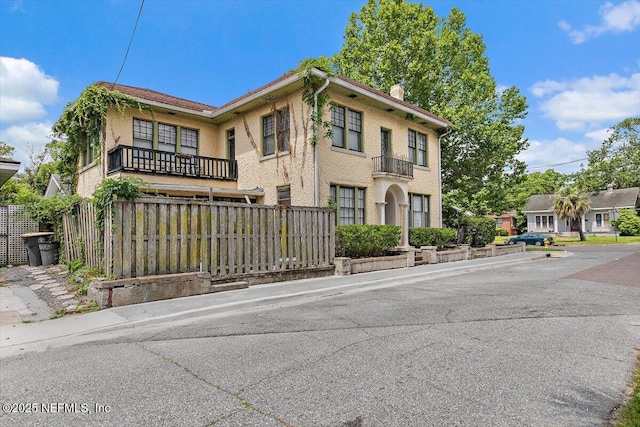 townhome / multi-family property featuring fence, a chimney, and a balcony