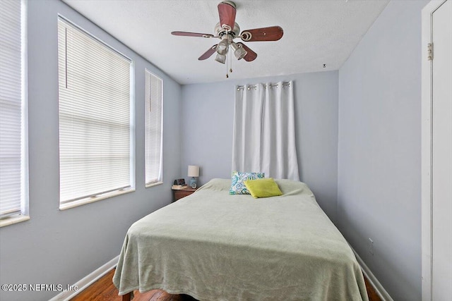 bedroom with baseboards, wood finished floors, and a ceiling fan
