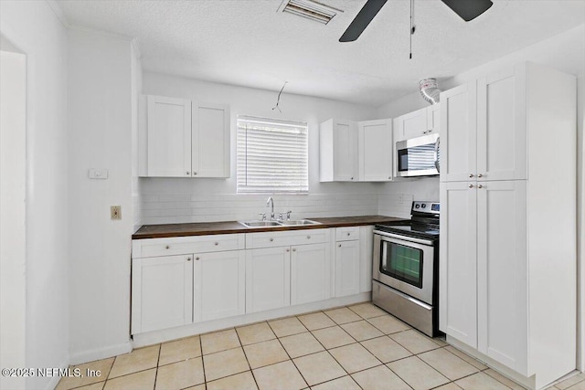 kitchen featuring appliances with stainless steel finishes, a sink, ceiling fan, white cabinets, and backsplash