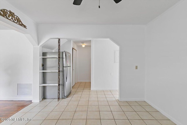 unfurnished room featuring ceiling fan, light tile patterned floors, ornamental molding, and baseboards