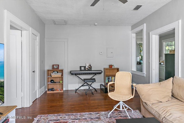 living room with wood finished floors, a ceiling fan, and a textured ceiling