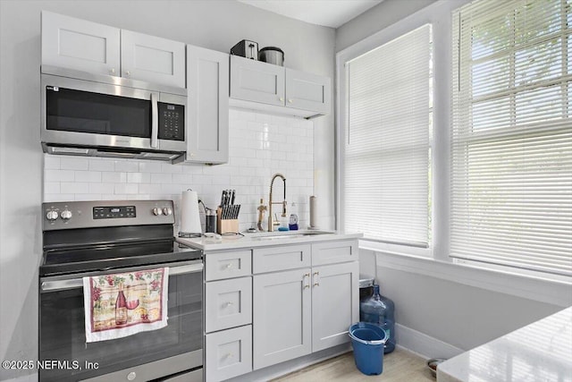 kitchen with stainless steel appliances, a sink, tasteful backsplash, and plenty of natural light