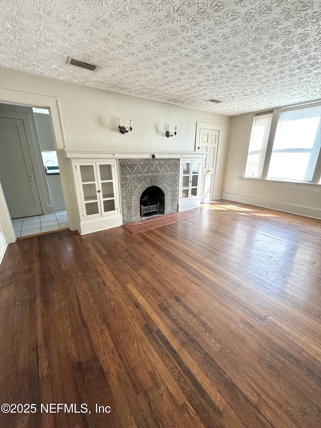 unfurnished living room featuring hardwood / wood-style floors, a fireplace, and baseboards